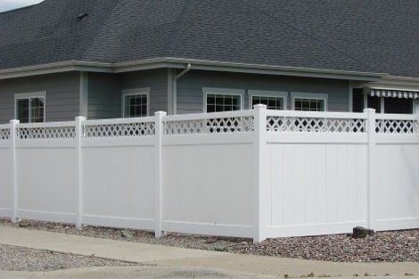 A white fence is in front of a house.