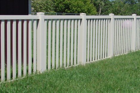 A white fence is sitting in the middle of a lush green field.