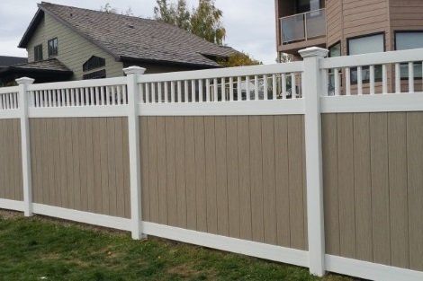 A brown and white fence is in front of a house.