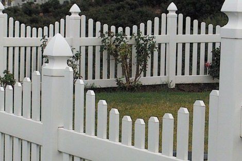 A white picket fence surrounds a lush green yard.