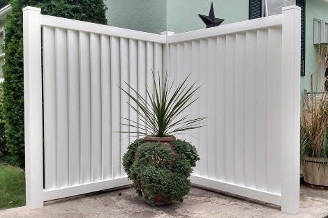 A white fence with a potted plant in front of it.