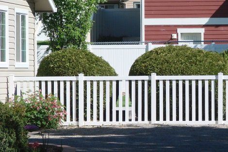 A white fence is in front of a red house