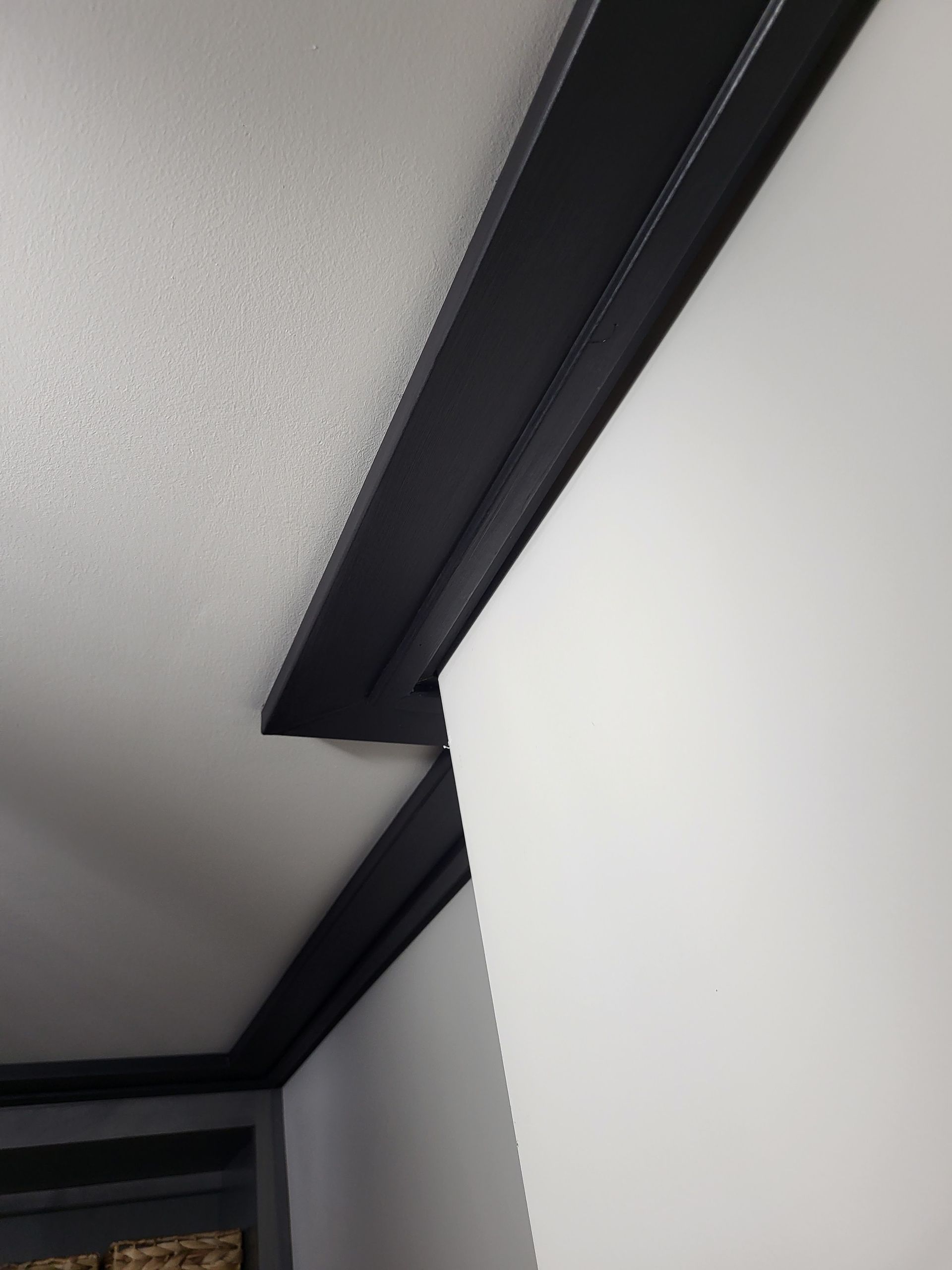 Interior corner with white walls and dark trim along the ceiling.
