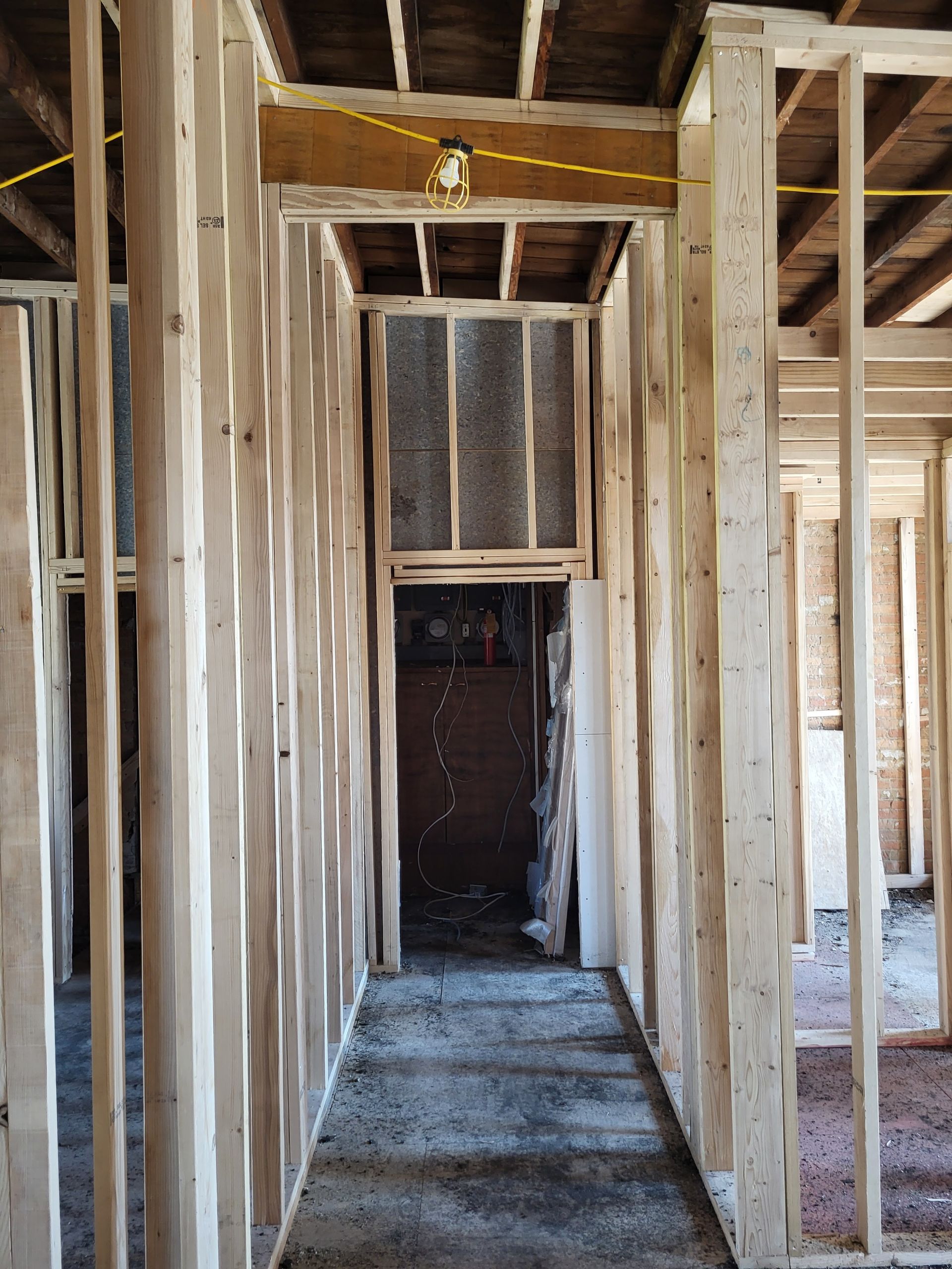 Unfinished house interior with exposed wooden framing and a narrow hallway