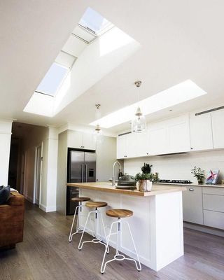 Bright White Kitchen With Skylights, Island, Wooden Stools — R&M Sheetmetal Nowra Metal Roofing in South Nowra, NSW