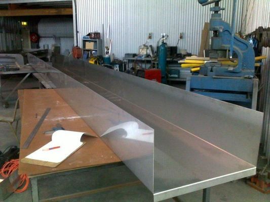 Two Long Metal Sheets Are on a Table in a Workshop, Alongside Tools — R&M Sheetmetal Nowra Metal Roofing in South Nowra, NSW