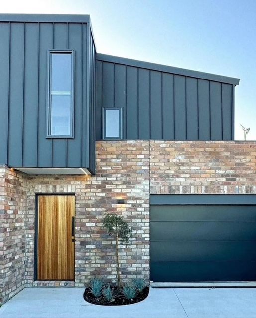 A brick house with a black garage door and a wooden door — R&M Sheetmetal Nowra Metal Roofing in Culburra, NSW