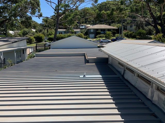 View of gray metal roofs on buildings with trees and houses in the background. — R&M Sheetmetal Nowra Metal Roofing in South Nowra, NSW