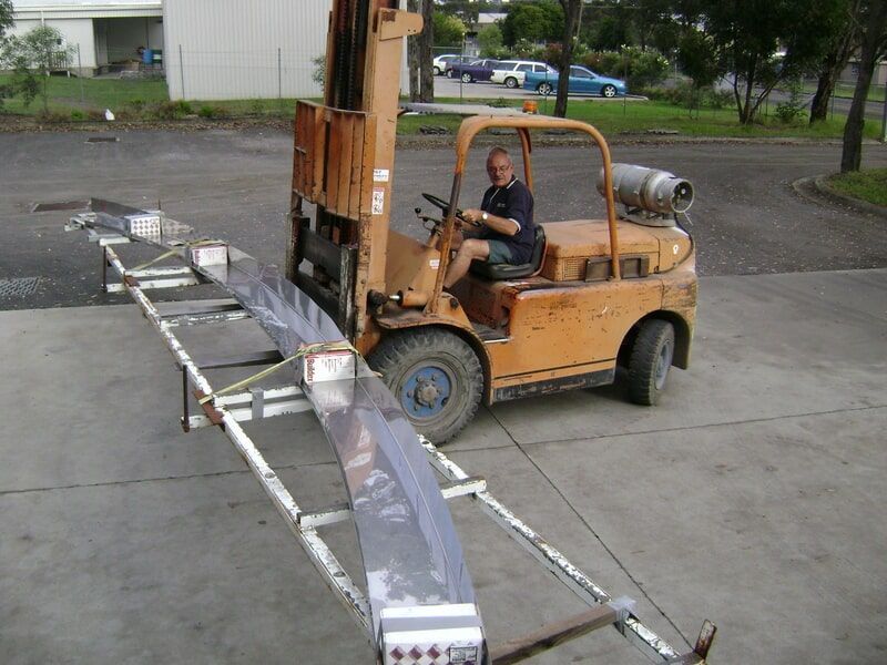 A Man Is Driving a Forklift in A Parking Lot — R&M Sheetmetal Nowra Metal Roofing in South Nowra, NSW
