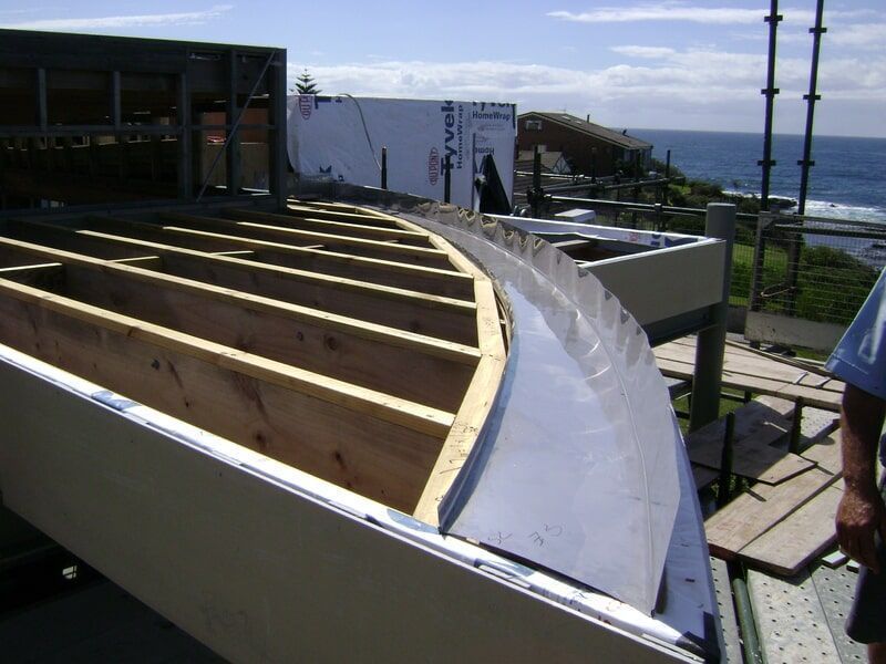 A Person Standing on Top of A Wooden Structure with The Ocean in The Background — R&M Sheetmetal Nowra Metal Roofing in South Nowra, NSW