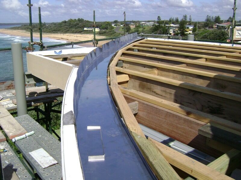 A Curved Roof Is Being Built with A Beach in The Background — R&M Sheetmetal Nowra Metal Roofing in South Nowra, NSW