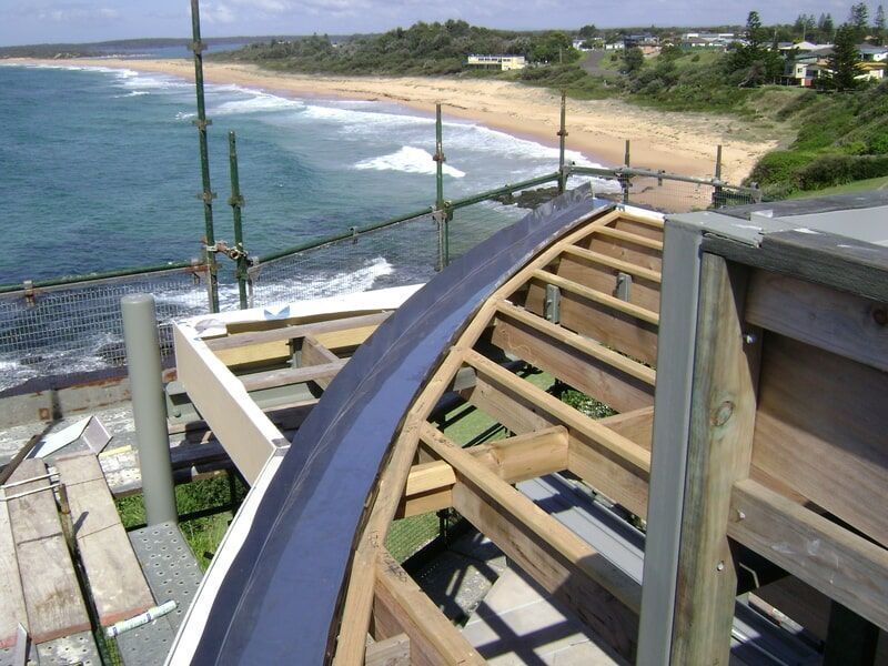 A Wooden Structure with A View of The Ocean in The Background — R&M Sheetmetal Nowra Metal Roofing in South Nowra, NSW