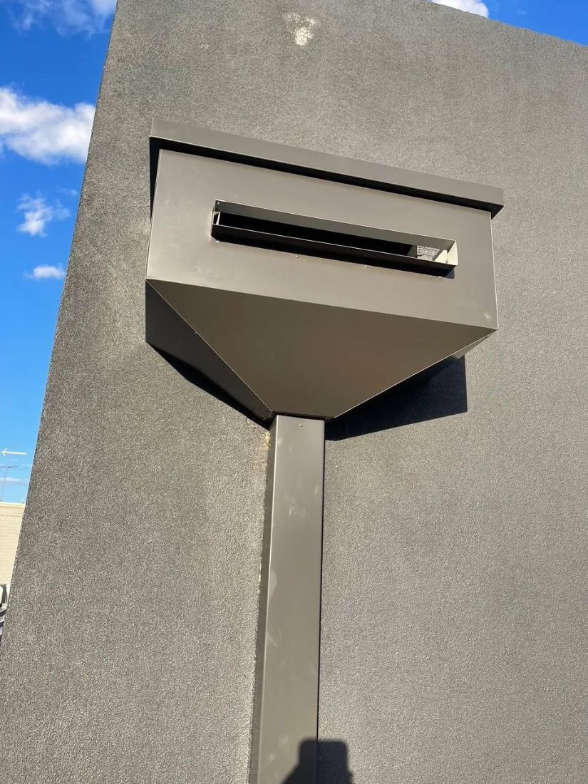A Mailbox Is Sitting on A Pole Next to A Wall — R&M Sheetmetal Nowra Metal Roofing in South Nowra, NSW