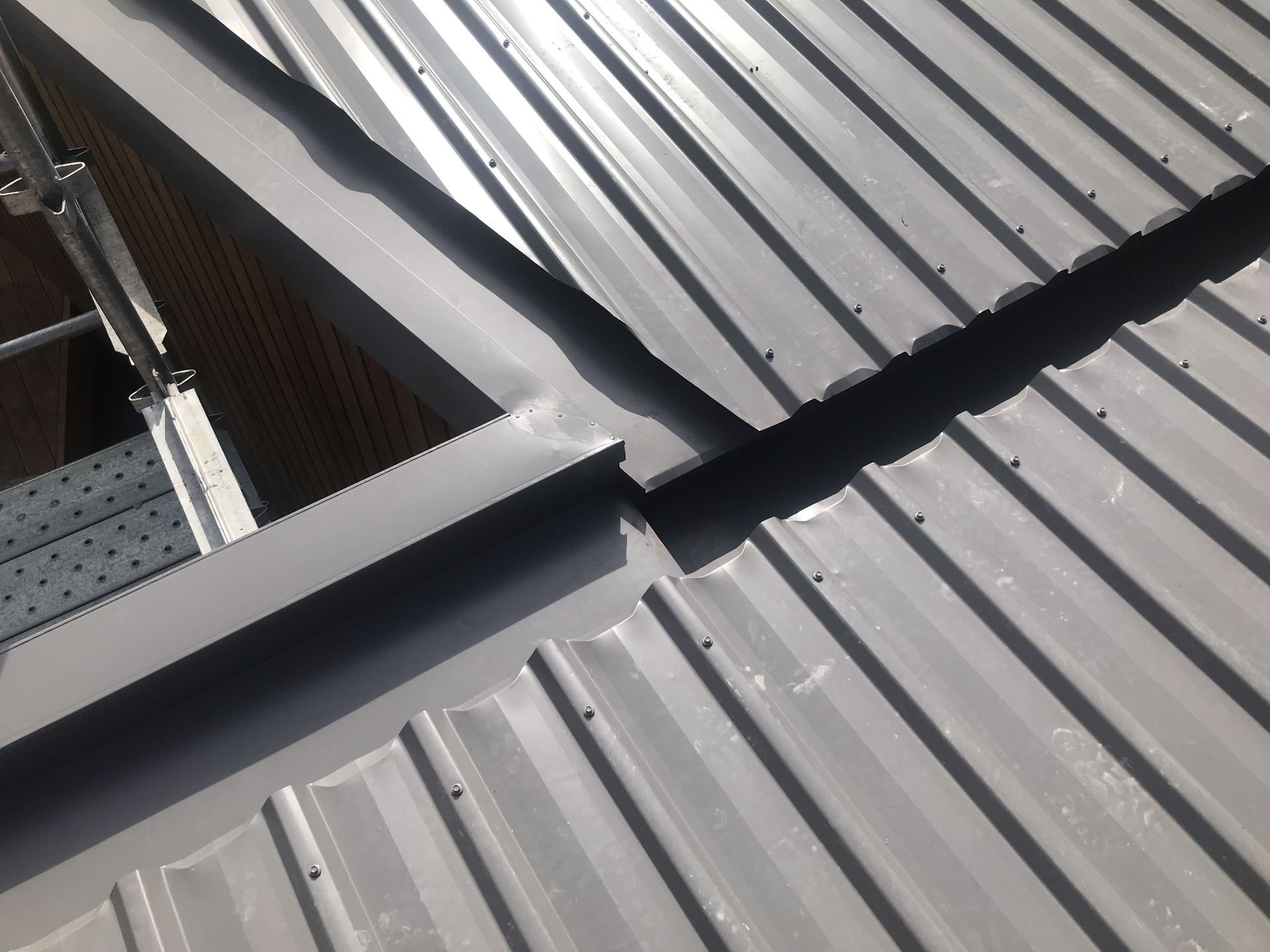 Gray metal roof with a skylight, showing overlapping metal sheets and sealed seams. — R&M Sheetmetal Nowra Metal Roofing in South Nowra, NSW