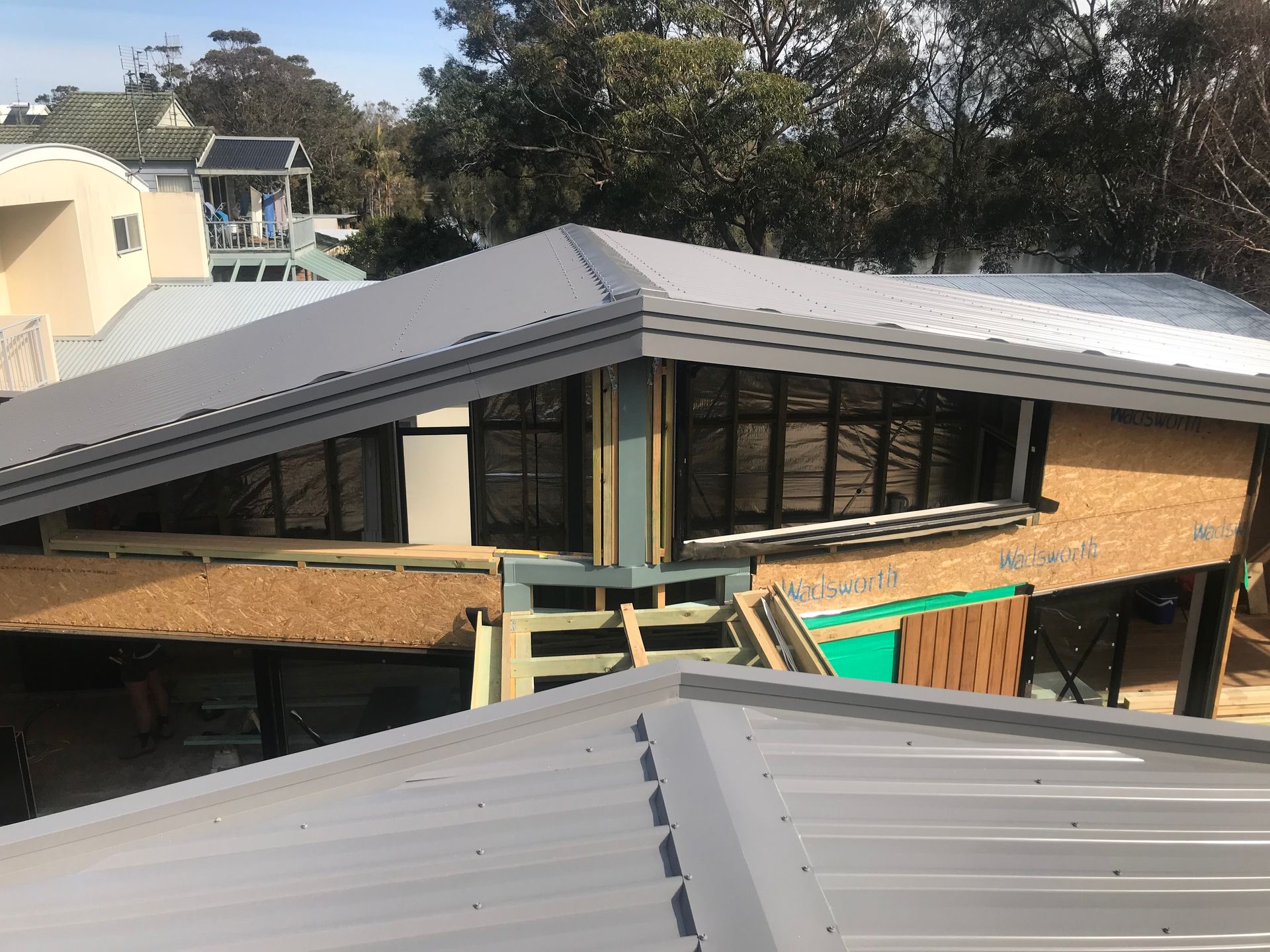House under construction with grey metal roof, exposed framing, and black windows. — R&M Sheetmetal Nowra Metal Roofing in South Nowra, NSW