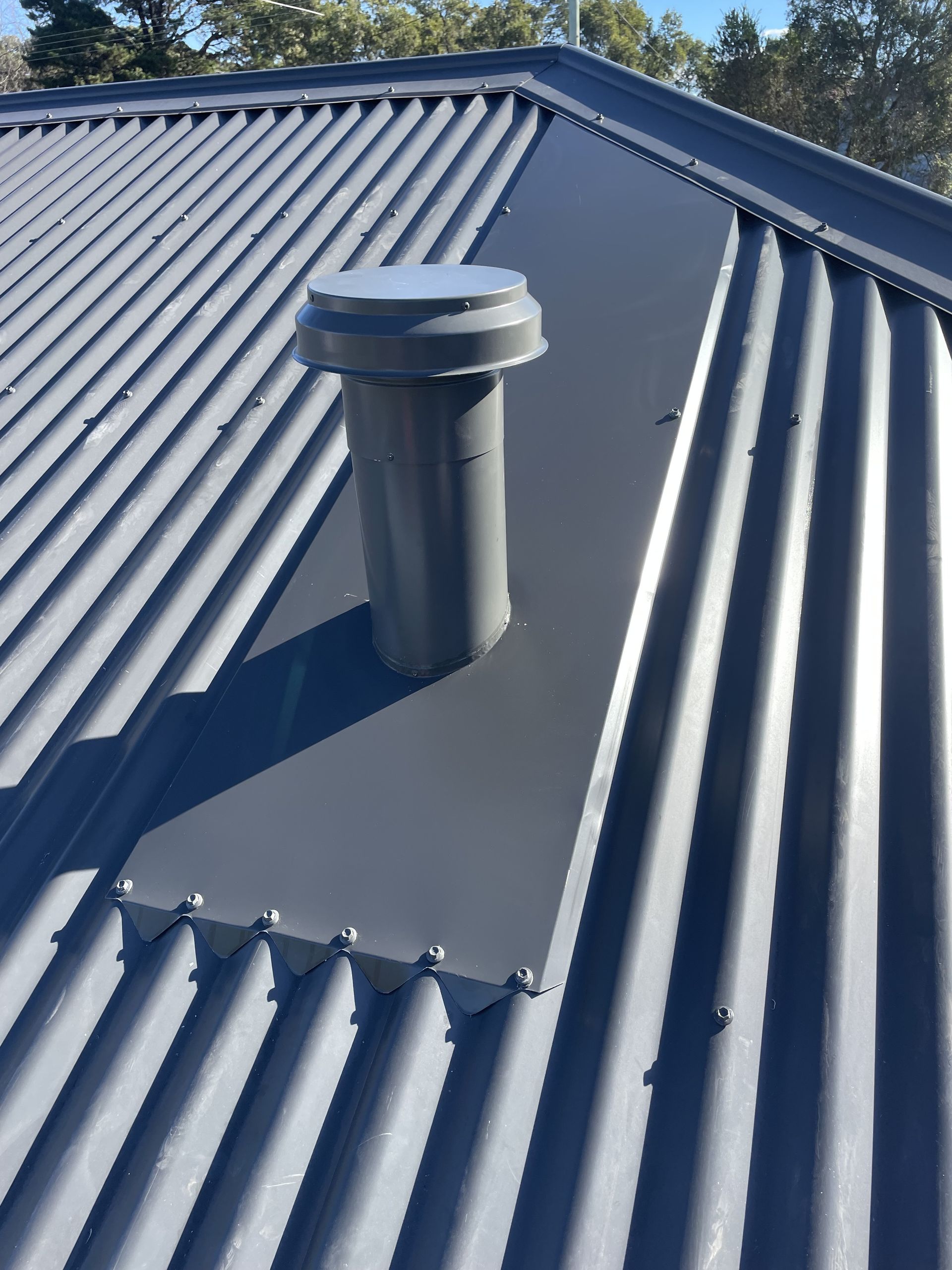Grey metal roof with a grey ventilation pipe and flashing. — R&M Sheetmetal Nowra Metal Roofing in South Nowra, NSW