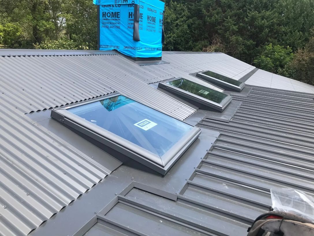 A Man Is Working on A Roof with A Skylight — R&M Sheetmetal Nowra Metal Roofing in South Nowra, NSW