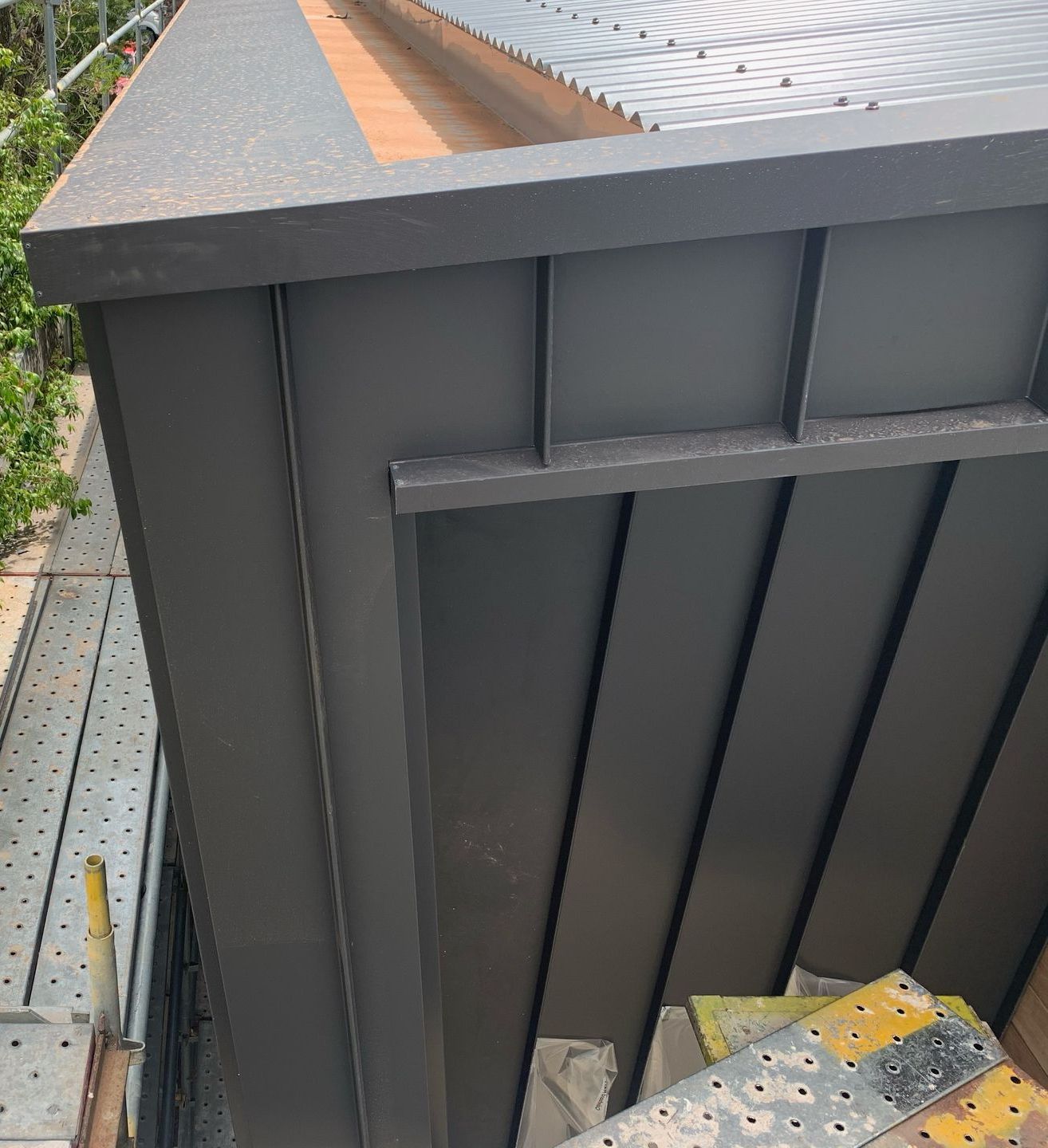 A black building with a roof and a ladder on the side of it. — R&M Sheetmetal Nowra Metal Roofing in South Nowra, NSW