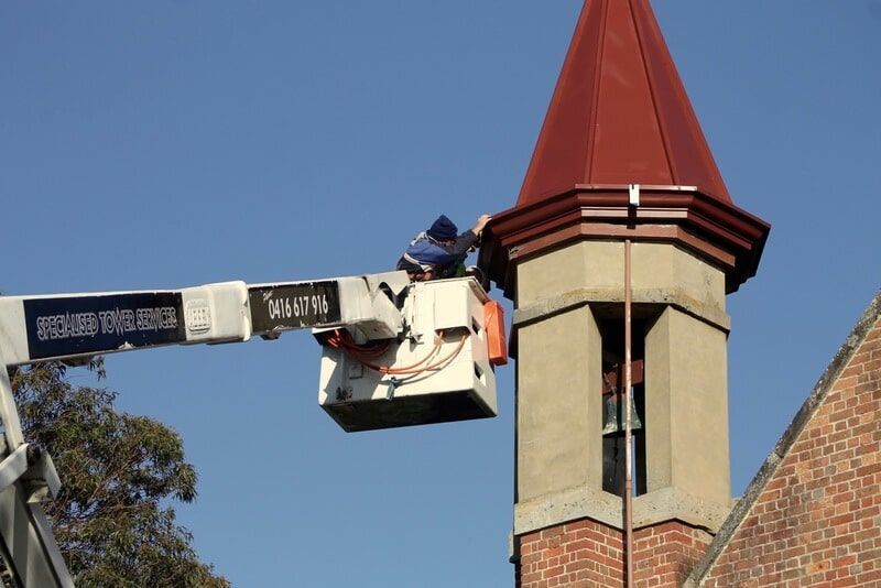 A Man in A Bucket Is Working on A Brick Building — R&M Sheetmetal Nowra Metal Roofing in South Nowra, NSW