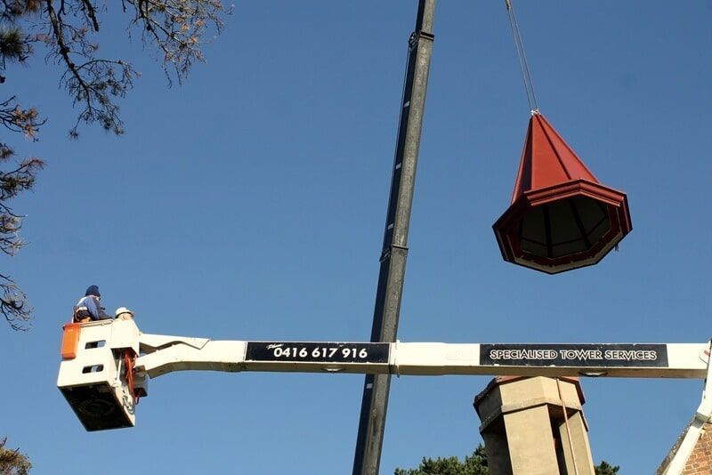 A Crane Is Lifting a Red Object Over a Chimney — R&M Sheetmetal Nowra Metal Roofing in South Nowra, NSW