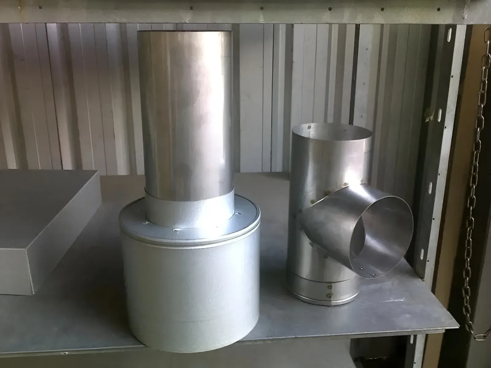 Two metal pipes are sitting on a metal shelf — R&M Sheetmetal Nowra Metal Roofing in Sussex, NSW