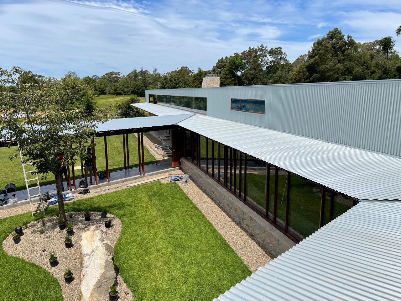 An aerial view of a large building with a covered walkway leading to it. — R&M Sheetmetal Nowra Metal Roofing in Culburra, NSW