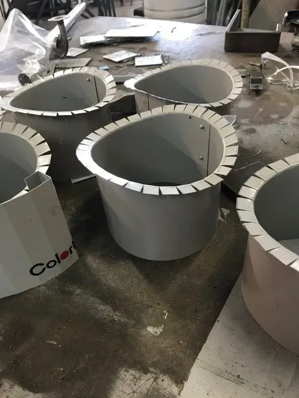 Gray metal cylinders with scalloped rims on a work surface, one with