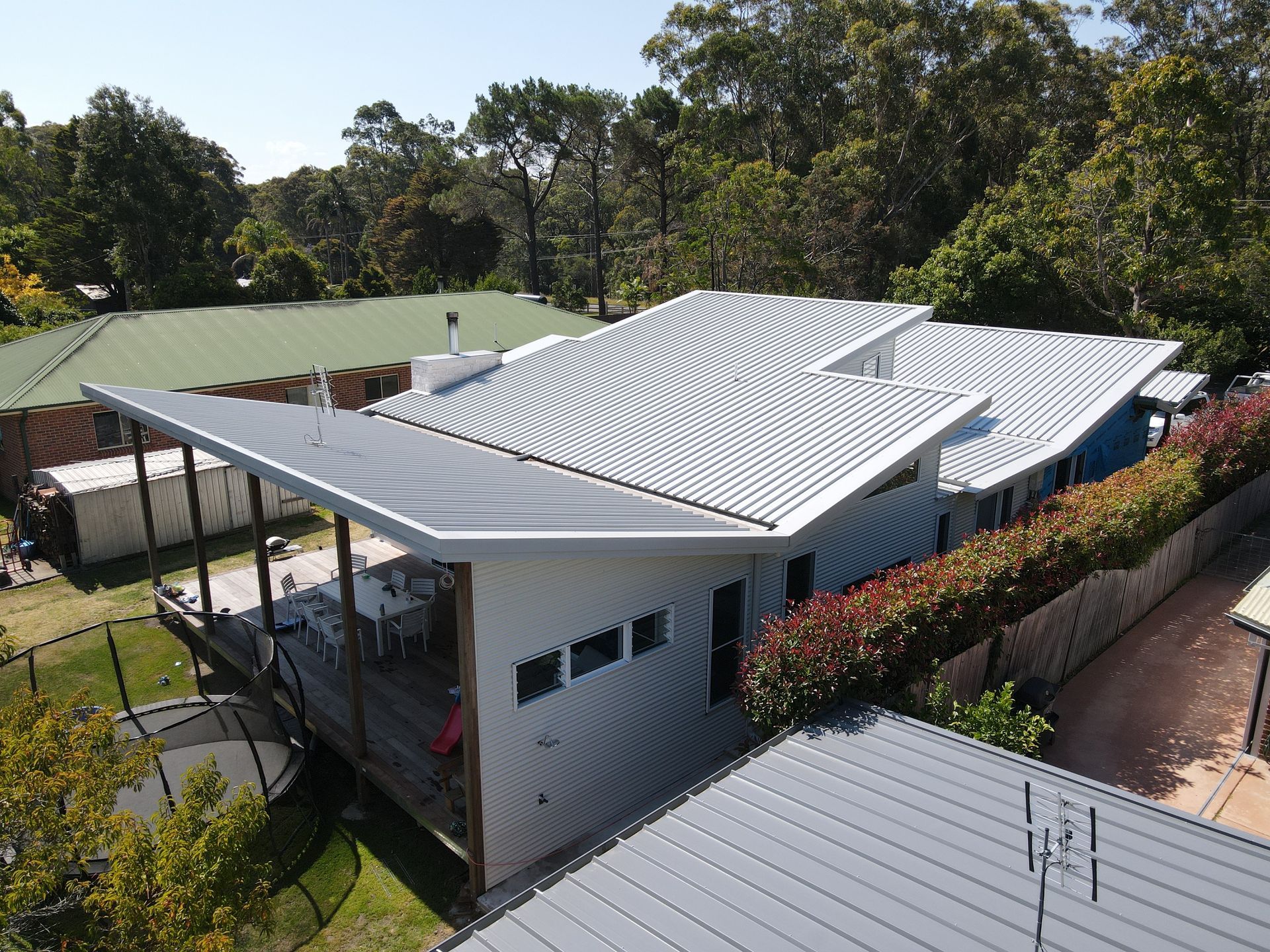 Modern house with corrugated metal roof and deck, surrounded by trees. — R&M Sheetmetal Nowra Metal Roofing in South Nowra, NSW