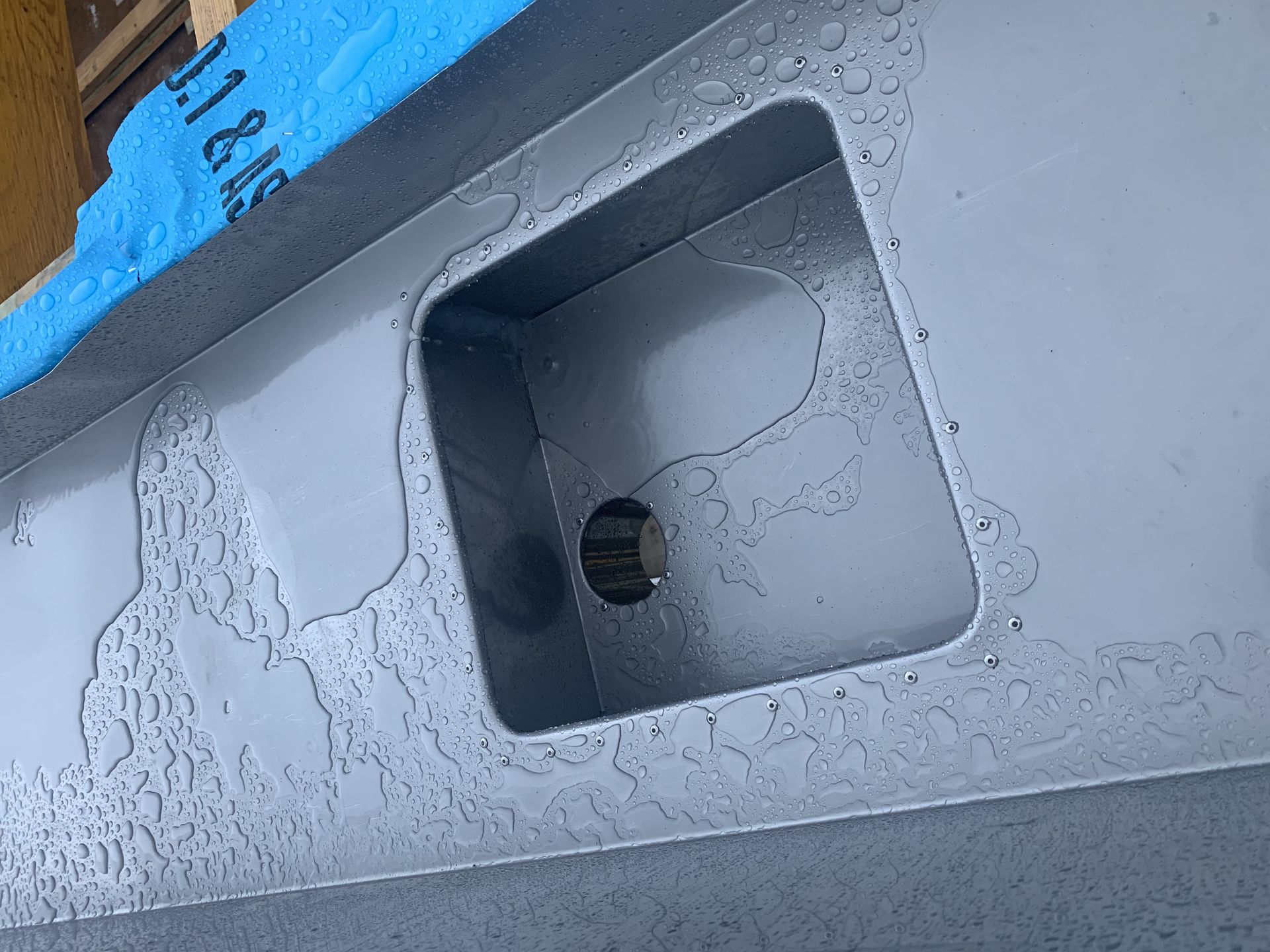 Gray metal surface with a rectangular cutout and circular hole. Water droplets are visible. — R&M Sheetmetal Nowra Metal Roofing in South Nowra, NSW