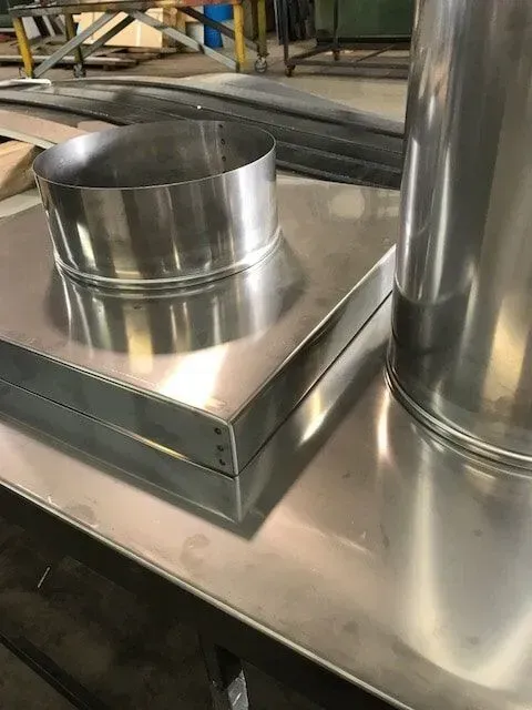 Two Stainless Steel Pipes Are Sitting on Top of A Metal Table — R&M Sheetmetal Nowra Metal Roofing in South Nowra, NSW