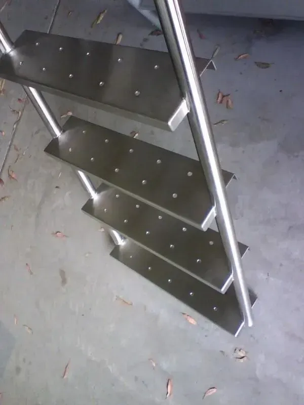 A stainless steel staircase is sitting on a concrete floor — R&M Sheetmetal Nowra Metal Roofing in Culburra, NSW