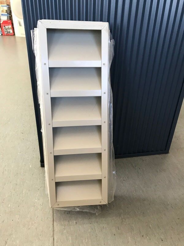 A White Shelf Is Sitting on The Floor in Front of A Blue Wall — R&M Sheetmetal Nowra Metal Roofing in Vincentia, NSW