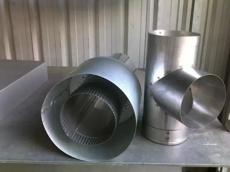 Two galvanized metal ductwork components on a metal surface. — R&M Sheetmetal Nowra Metal Roofing in South Nowra, NSW