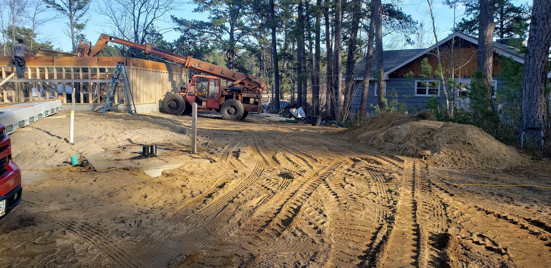 Construction site with a house and machinery, dirt.