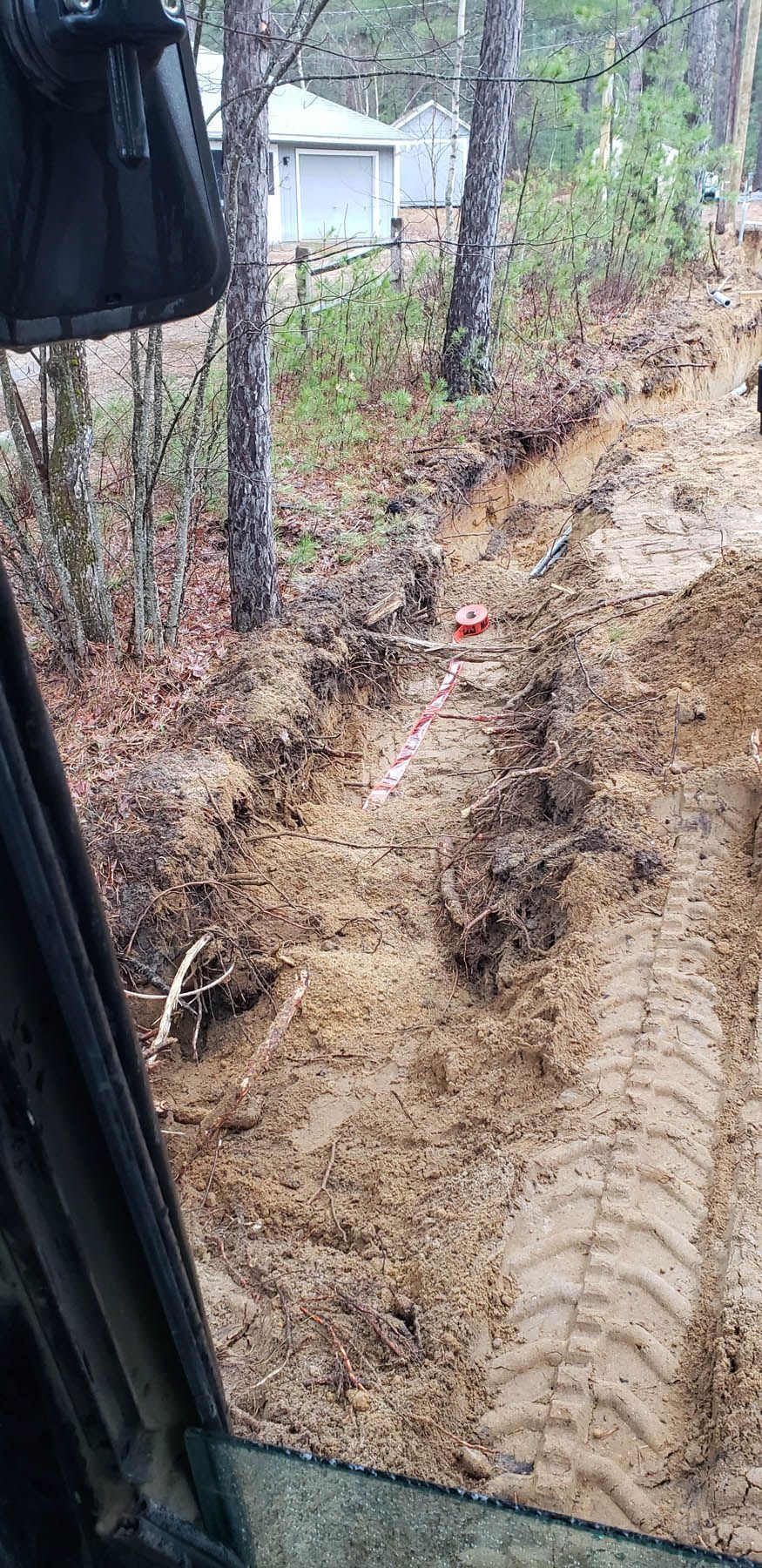 Muddy ground, tire tracks. A white building visible in the distance.