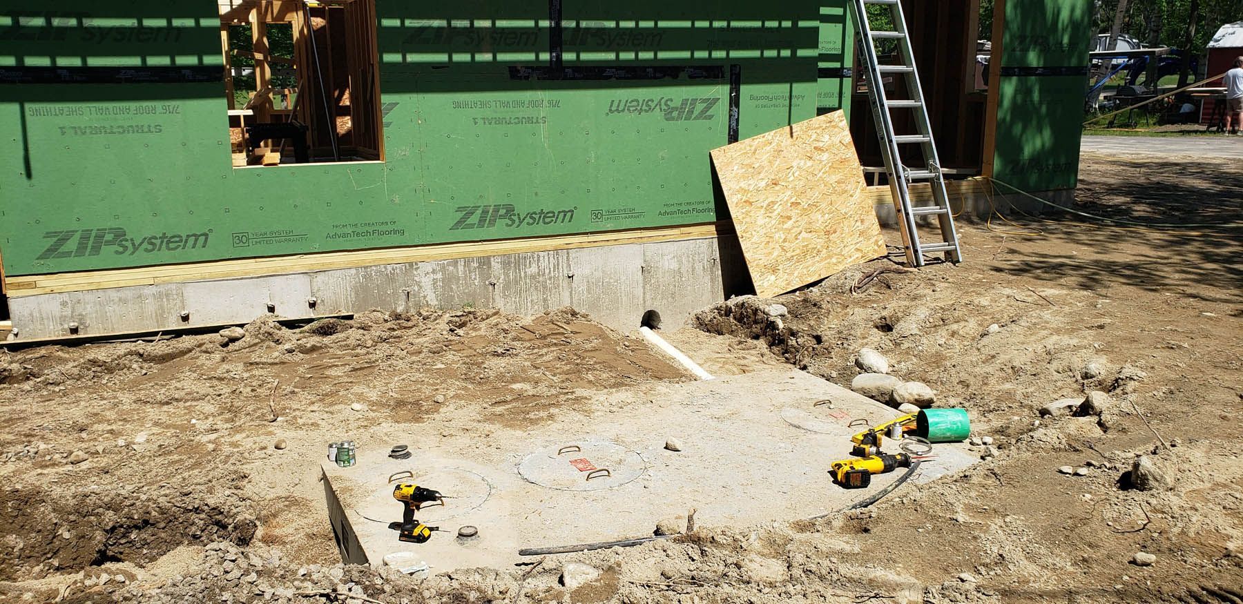 Construction site with a concrete slab, tools, and green siding.
