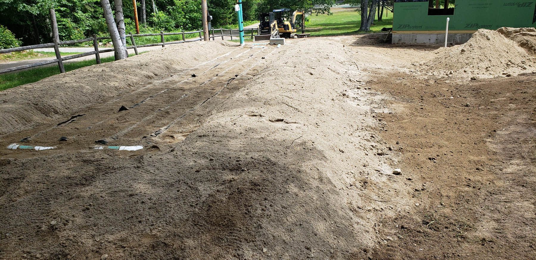 A construction site with piles of dirt, machinery, and partial building in the background.