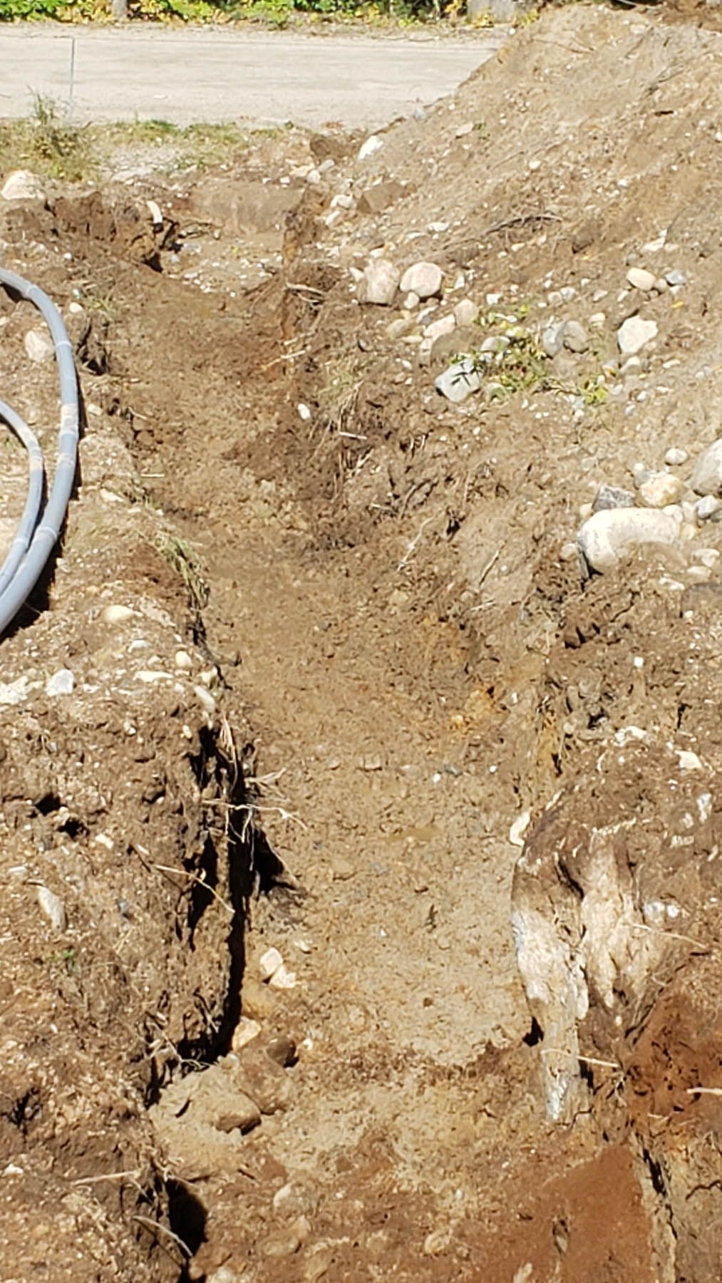 A dirt trench dug in the ground, potentially for laying a pipe or cable.