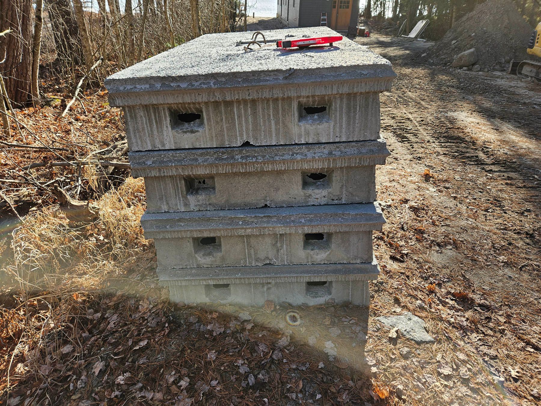 Concrete blocks stacked, forming a beehive-like structure, outdoors with surrounding foliage.