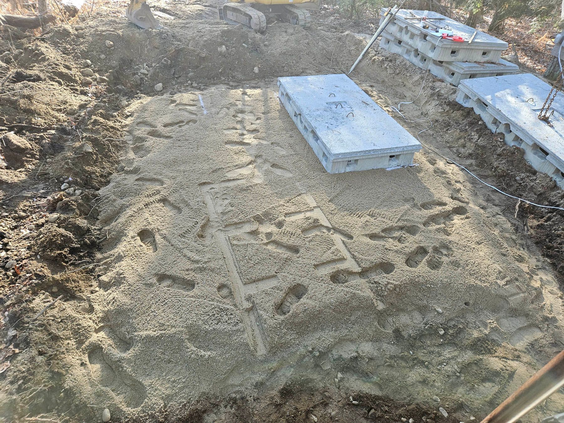 Construction site with excavated ground, gravel base, and concrete slabs.