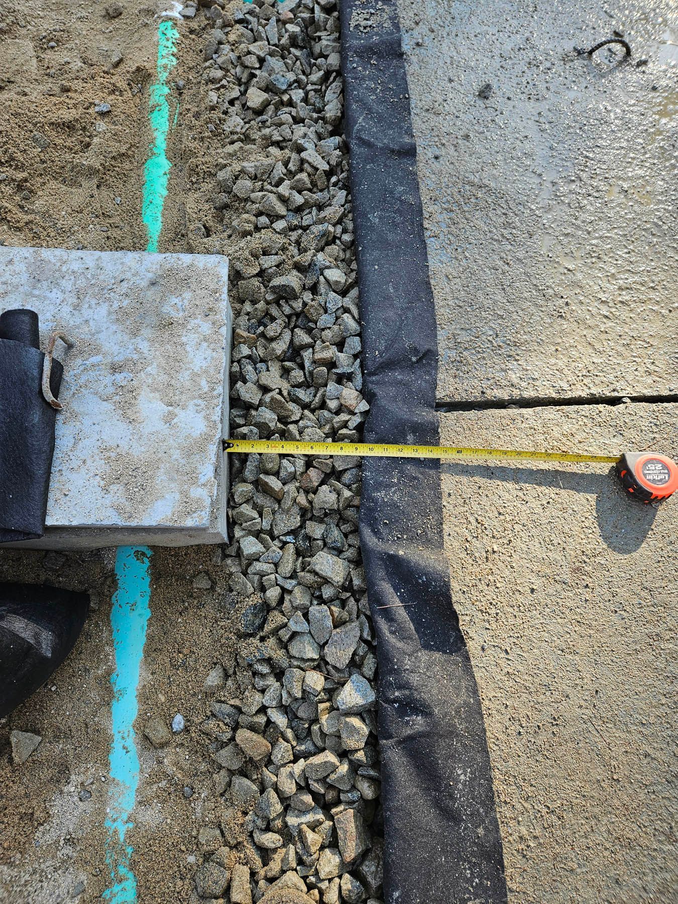 Gravel landscaping next to concrete with a tape measure showing a narrow width.