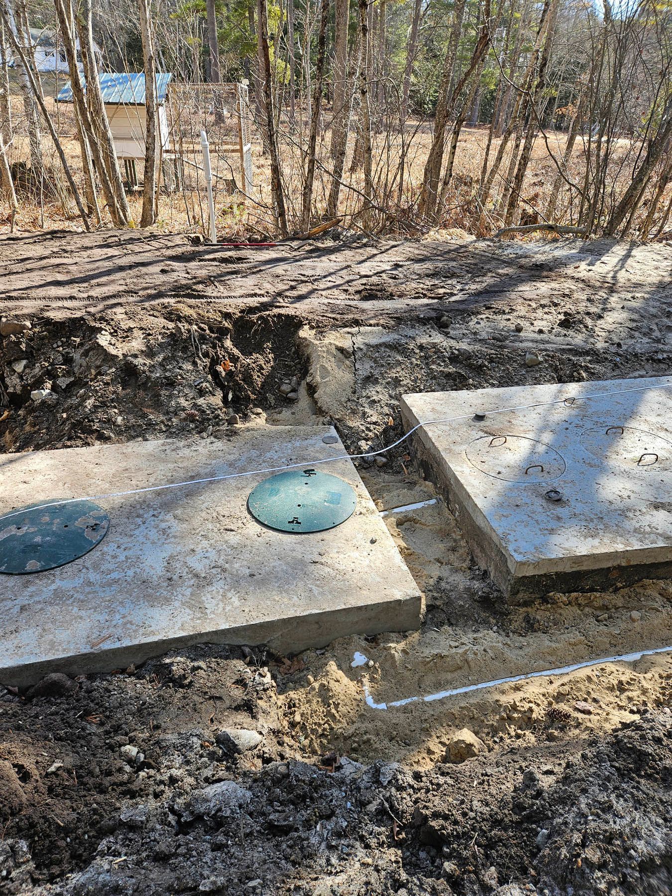 Septic tank installation: concrete tanks in a trench, pipes, and dirt.