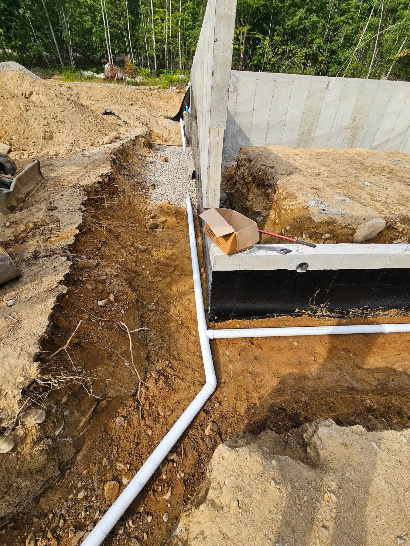 Foundation drainage system installation with white PVC pipe.