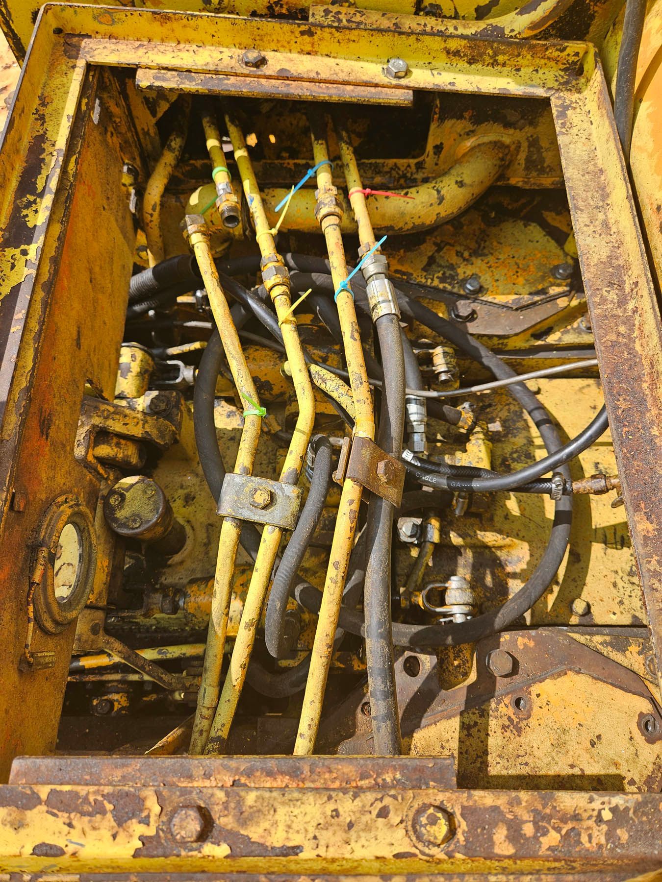 Yellow machinery interior with several hydraulic lines.