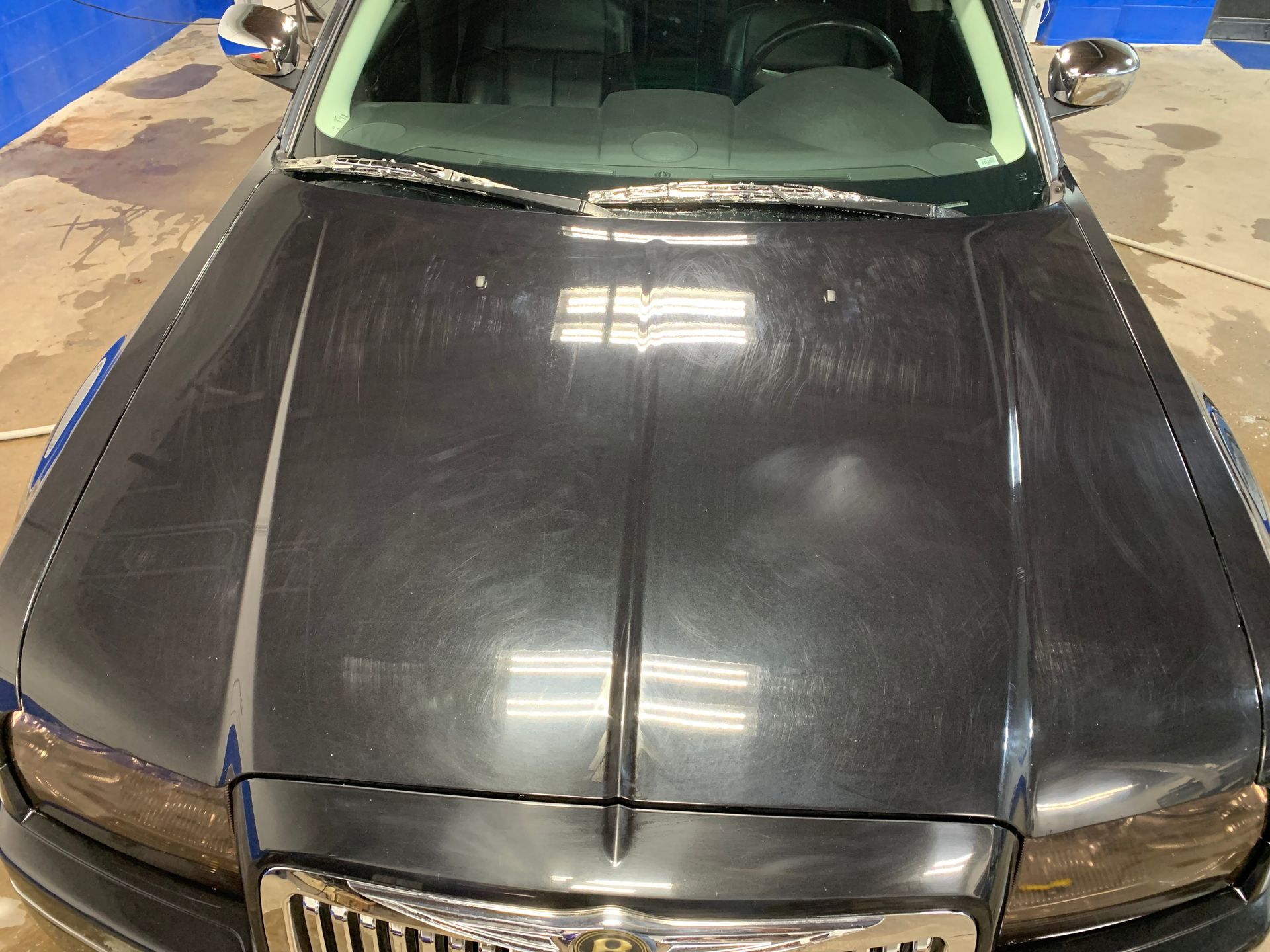 Dark gray car hood with scratches and reflections.