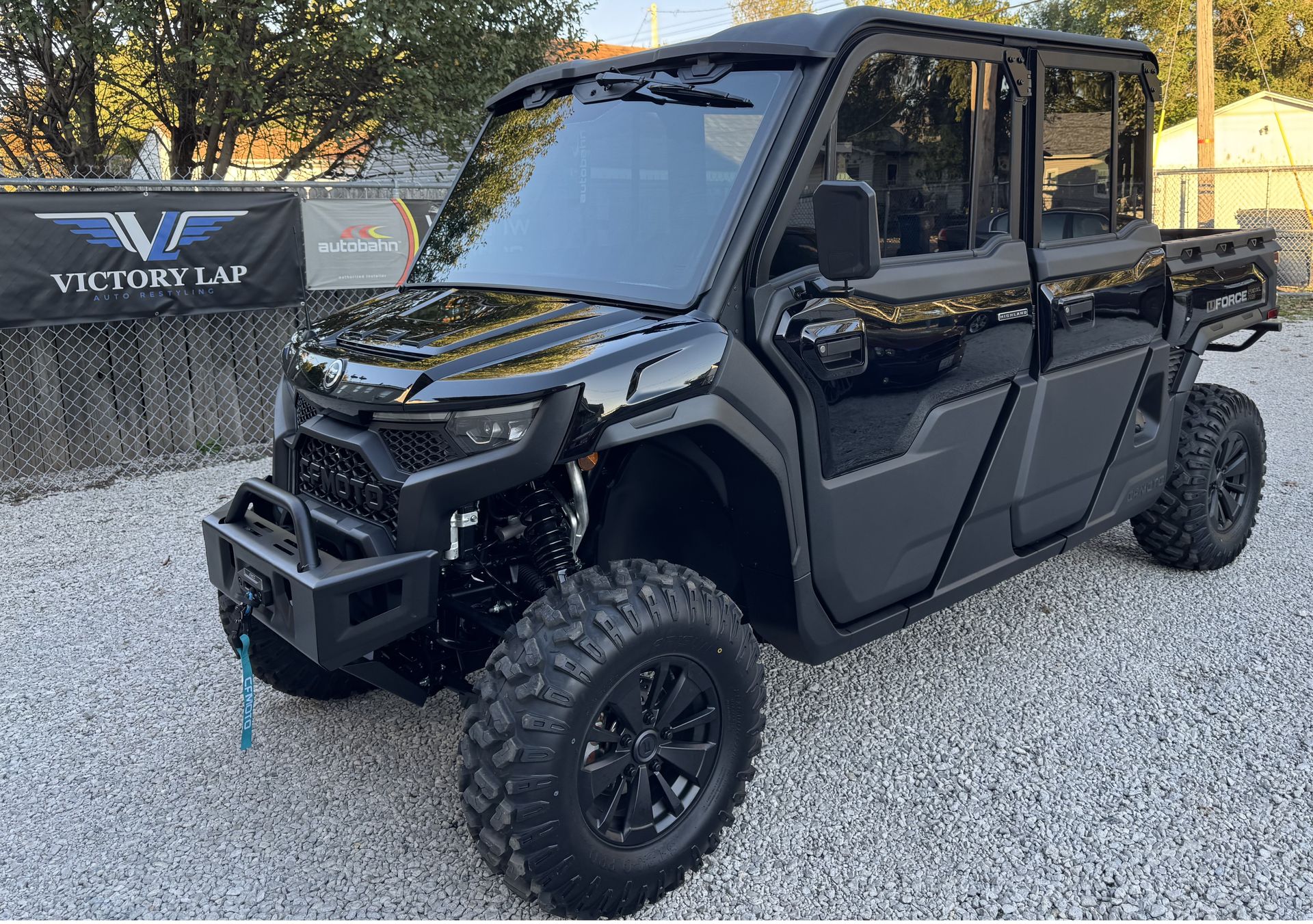 Black off-road utility vehicle with large tires, parked on gravel.