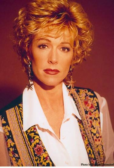 A woman wearing a white shirt and a floral vest