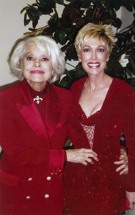Two women are posing for a picture and one is wearing a red jacket
