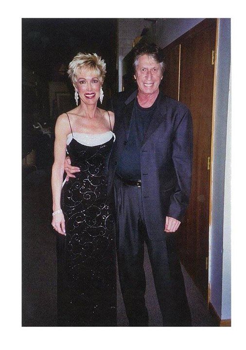 A man in a suit and a woman in a black dress pose for a photo