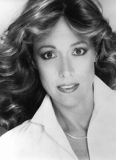 A black and white photo of a woman with long hair and a white shirt.